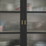 some dishware hidden inside of a furniture with corrugated glass