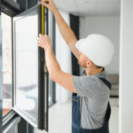 handsome young man installing bay window in new house construction site